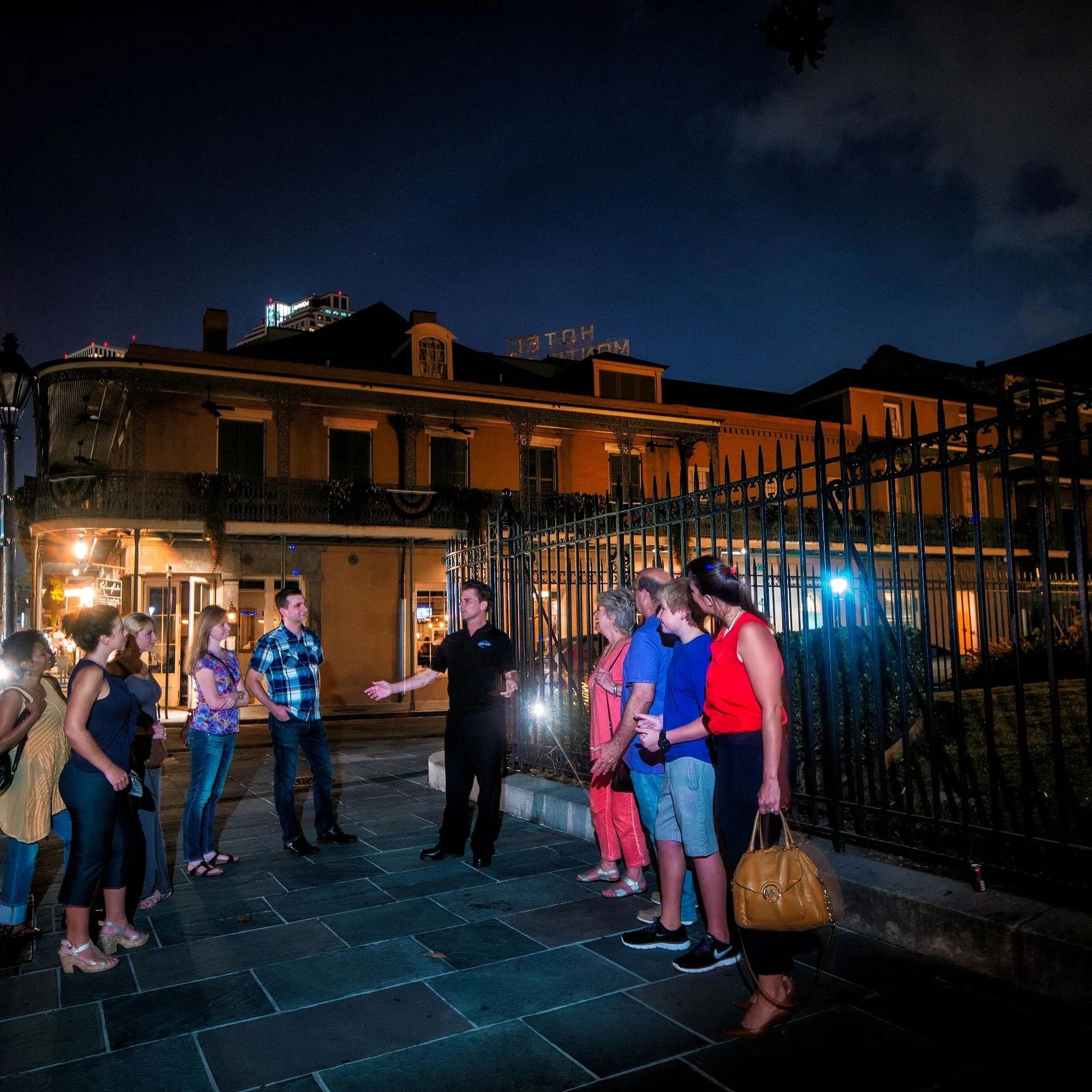 a group of people walking on a city street at night