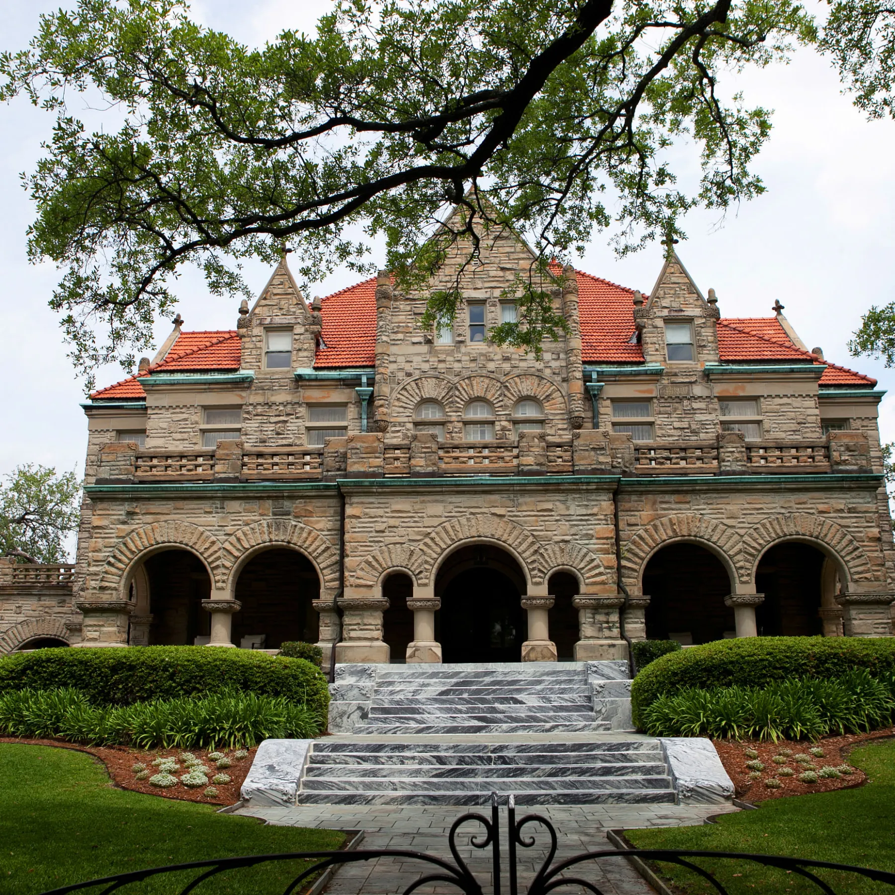 a stone bench sitting in front of a house with Rhodes Hall in the background