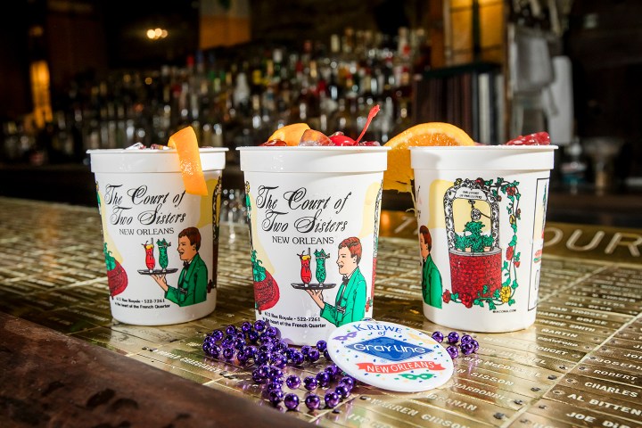 Three decorated cups with drinks and garnishes on a bar counter.