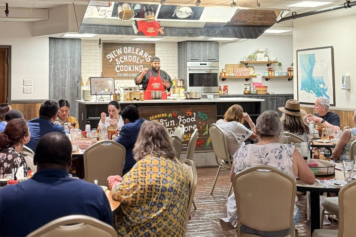 Chef demonstrating cooking to an audience in a classroom setting.