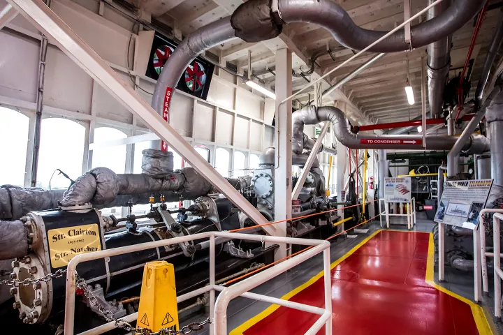 Interior of a steamboat engine room with pipes and machinery.