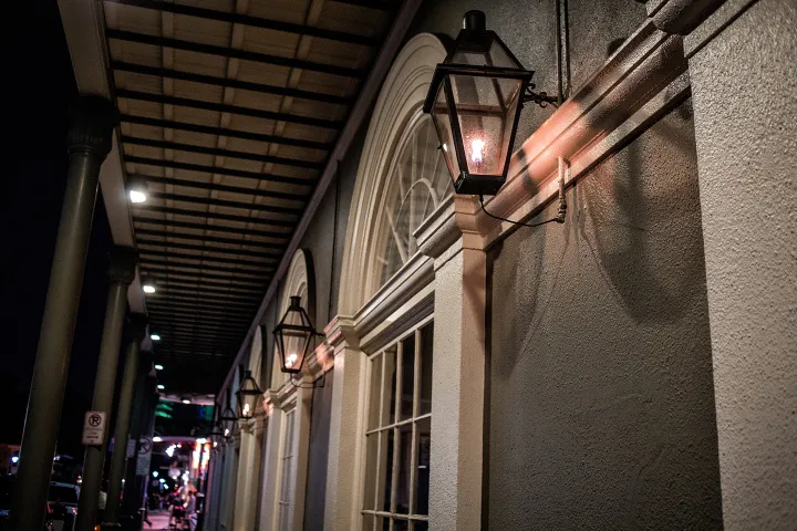 Dimly lit street with hanging lanterns under an awning at night.