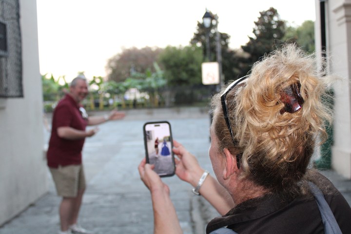 Woman photographing a man with a smartphone on a street.
