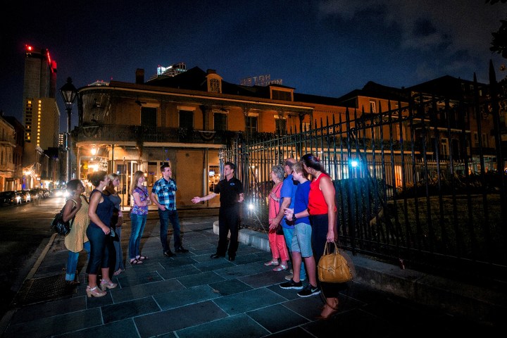 Tour group at night in front of an old building with a guide gesturing.
