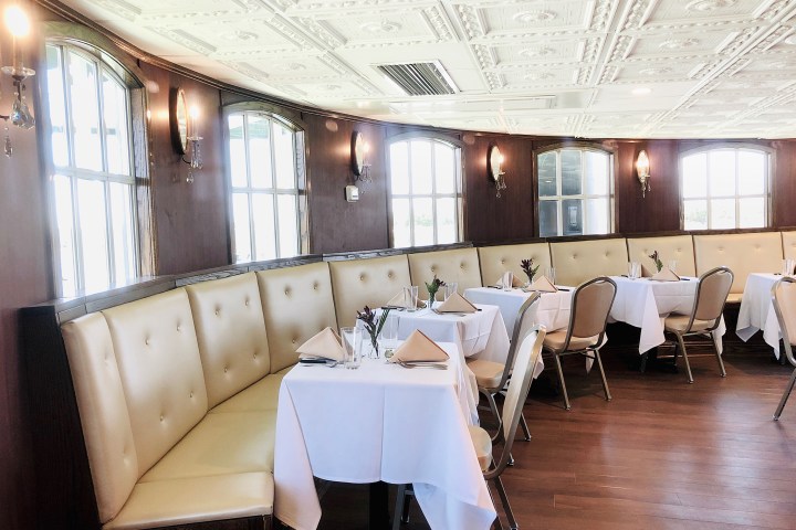 Elegant restaurant with white tablecloths, cushioned seating, and large windows.