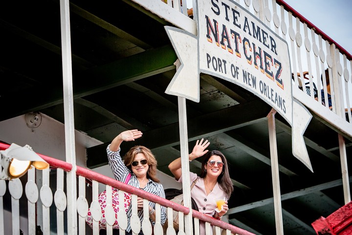 Two people wave from the deck of Steamer Natchez in New Orleans.