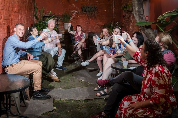 Group of people sitting and smiling while raising glasses in celebration.