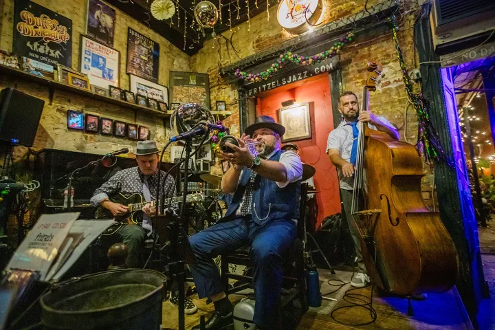 Jazz band performing in a cozy pub with trumpet, guitar, and double bass.