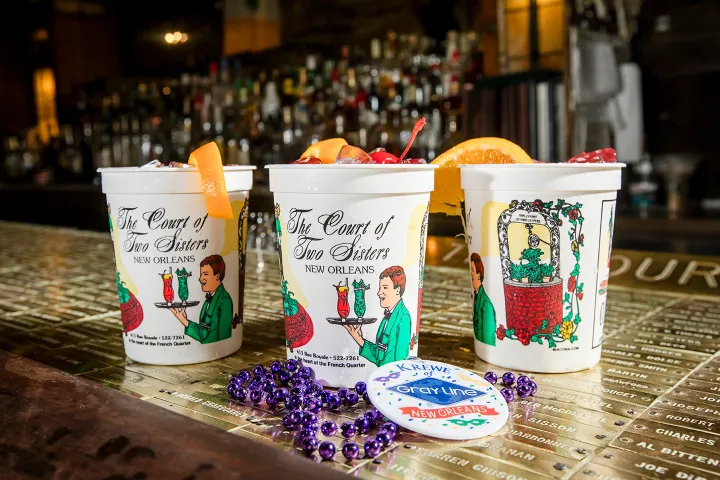Three decorated cups with garnishes and beads on a bar counter.