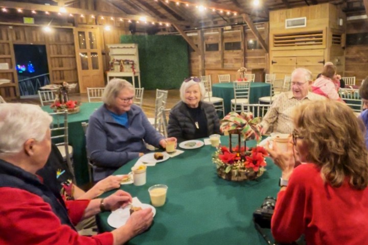 Group of people seated at a decorated table in a rustic room with string lights.