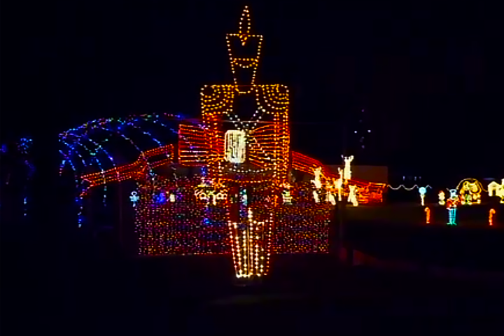 Colorful holiday lights featuring a large nutcracker and festive figures at night.