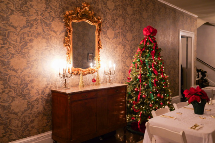 Elegant room with decorated Christmas tree, mirror, and candelabra on a sideboard.