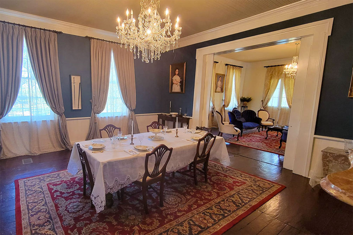Elegant dining room with chandelier, table set for four, and adjoining living area.
