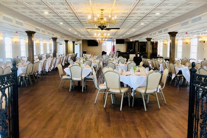 Elegant banquet hall with round tables, white tablecloths, and chandeliers.
