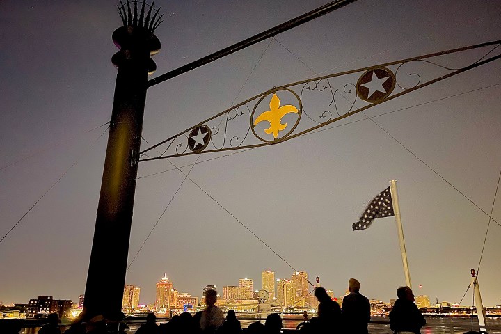 Silhouettes and flag with city skyline at night.