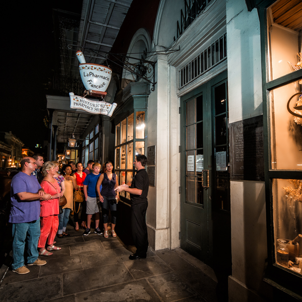 People on a nighttime tour outside a historic building.