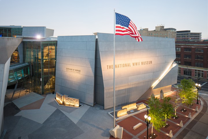 The National WWII Museum with an American flag and modern architecture at dusk.