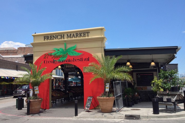 Entrance to French Market with Creole Tomato Festival sign and palm trees.